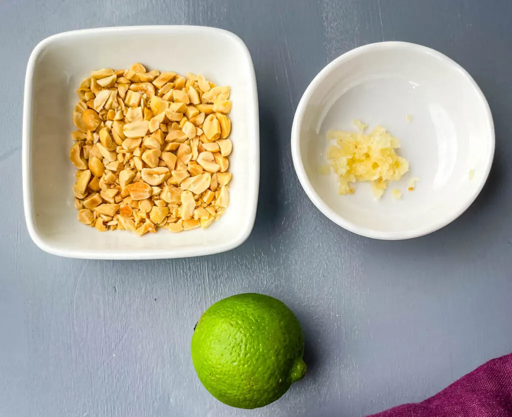 chopped peanuts, garlic, and a lime on a flat surface