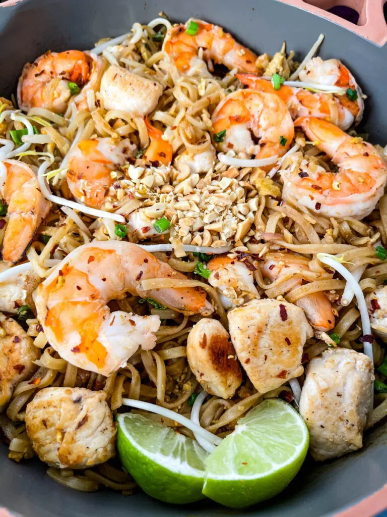healthy pad thai with chicken, shrimp, bean sprouts, and lime in a pan