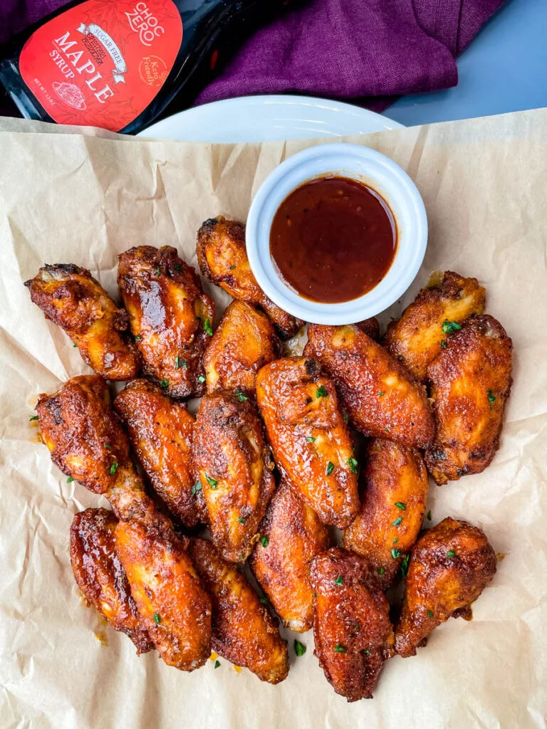 keto low carb chicken wings on a plate with maple syrup and BBQ sauce