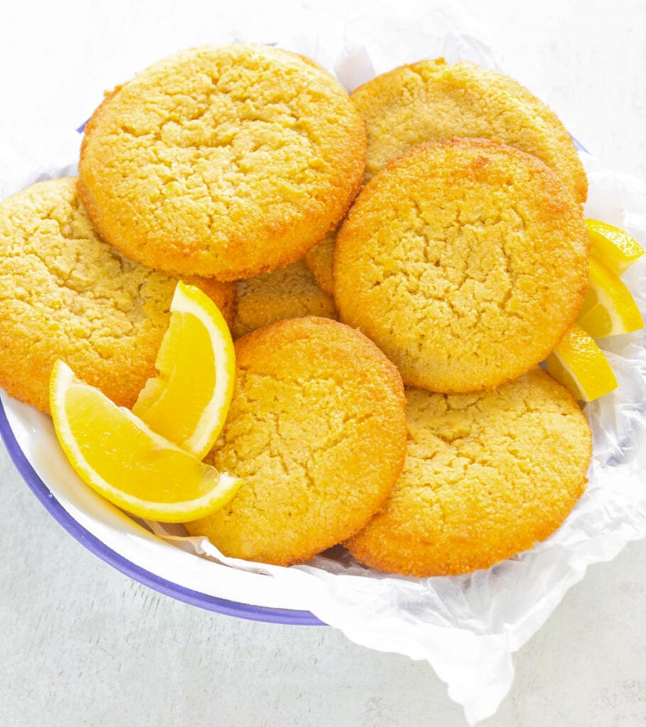 keto low carb lemon cookies on.a white plate with lemon wedges