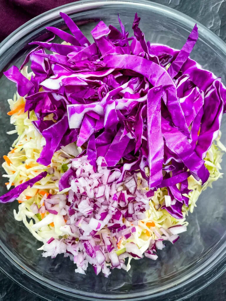 red cabbage, coleslaw mix, and chopped onions in a glass bowl