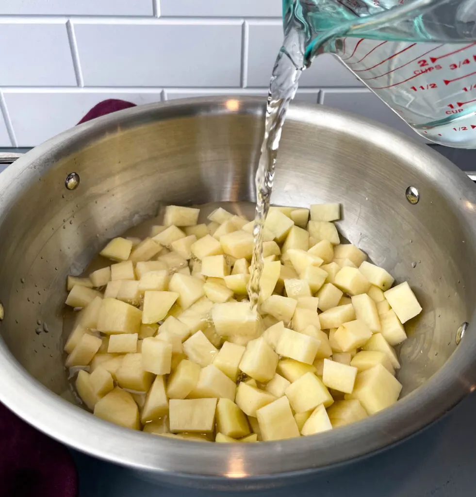 water poured into a pot with sliced potatoes