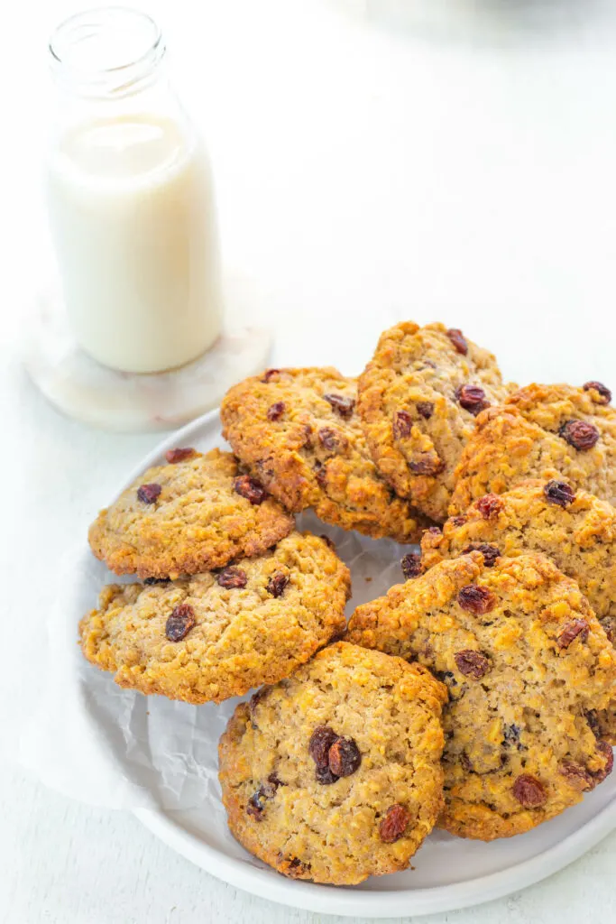 healthy sugar free oatmeal raisin cookie on a white plate with a glass of milk