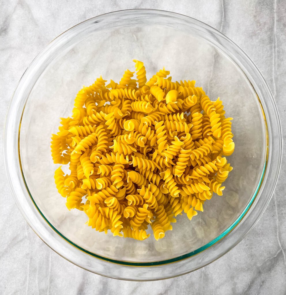 uncooked rotini pasta in a glass bowl