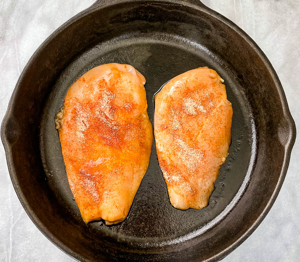 raw chicken breasts in a cast iron skillet