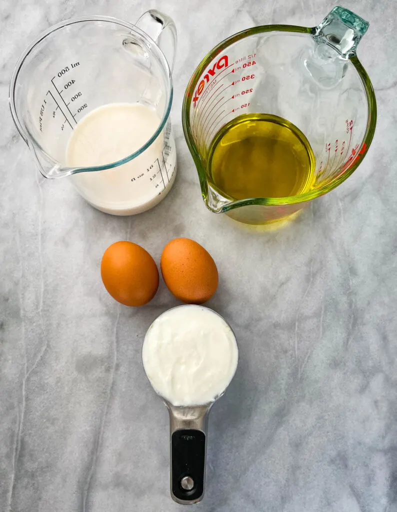 milk, olive oil, eggs, and Greek yogurt in separate bowls
