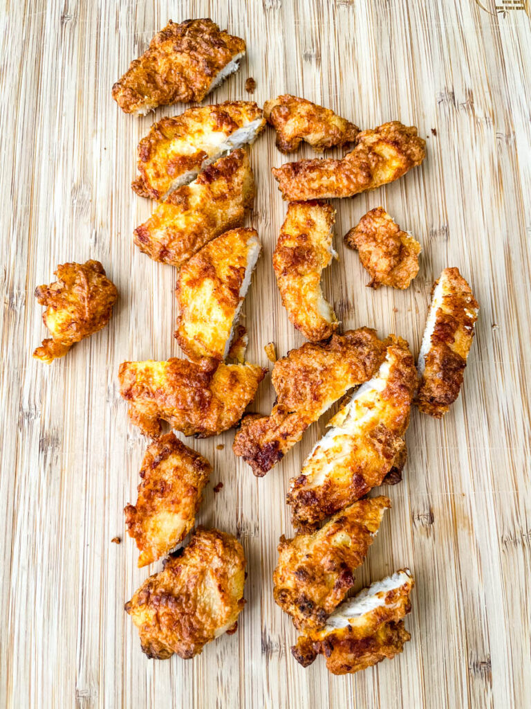 fried chicken tenders sliced on a cutting board