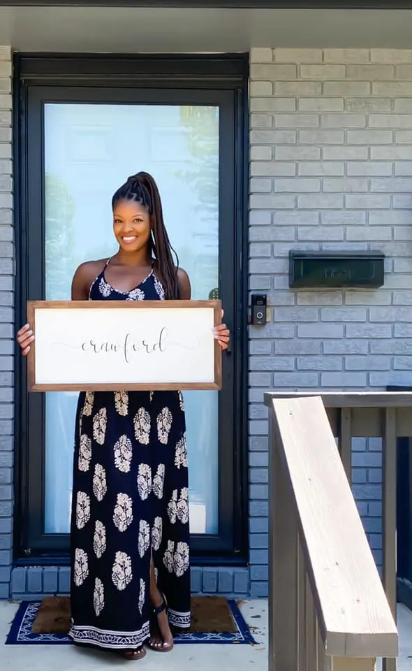 person standing in front of house with a sign