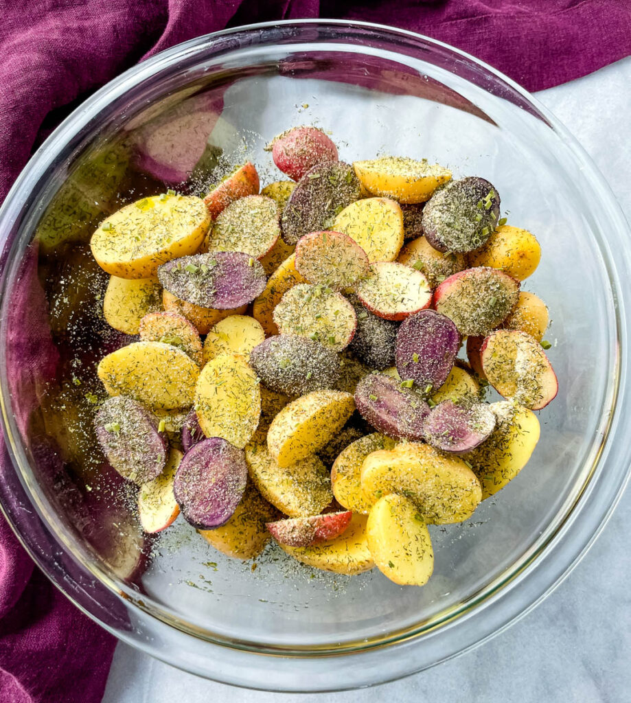 raw sliced potatoes in a glass bowl with homemade ranch seasoning