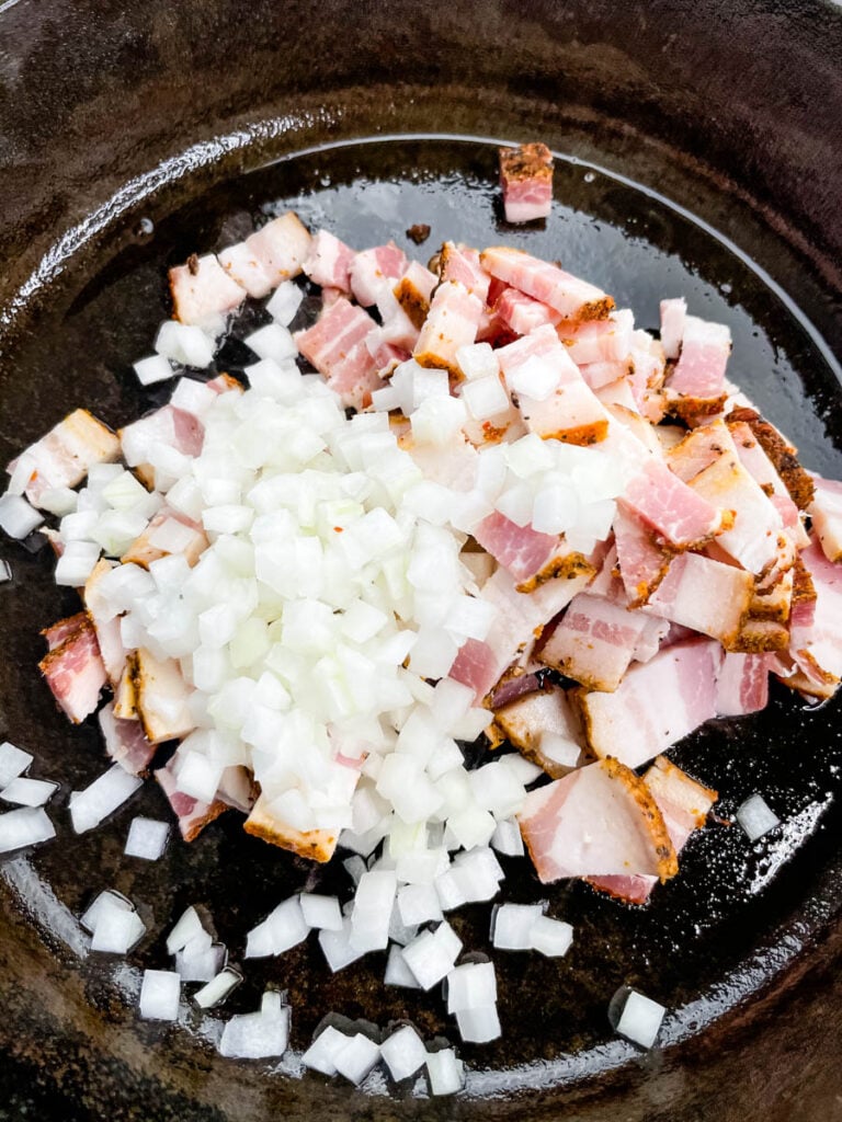 raw onions and bacon in a cast iron skillet