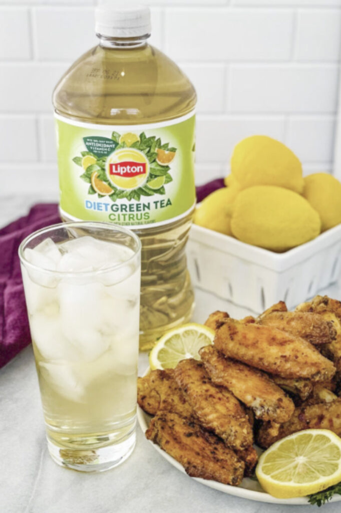 lemon pepper wings on a white plate with fresh lemon