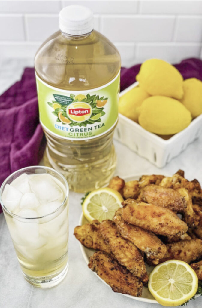 lemon pepper wings on a white plate with fresh lemon
