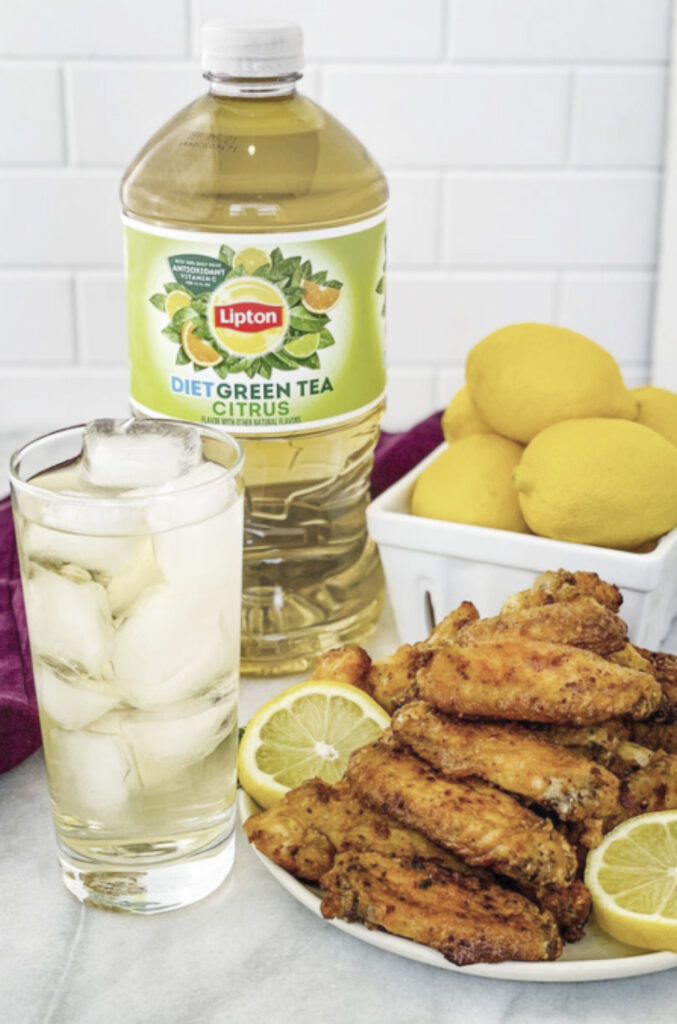 lemon pepper wings on a white plate with fresh lemon