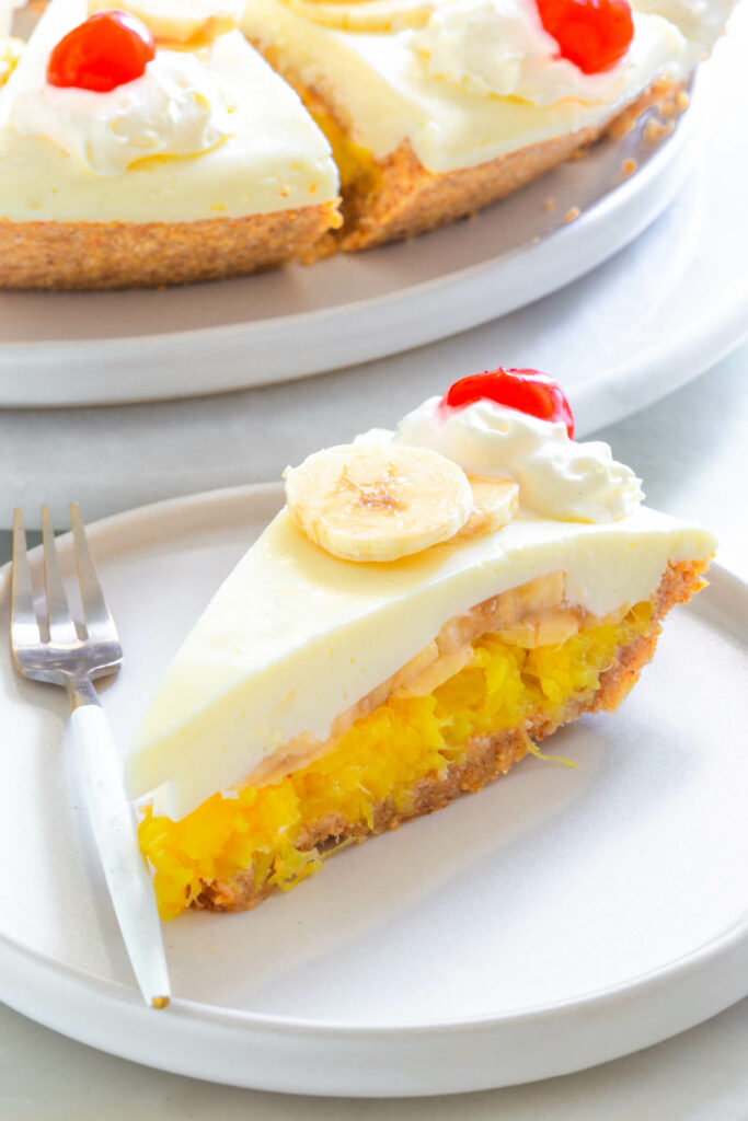 banana split pie on a plate with cherries and whipped cream