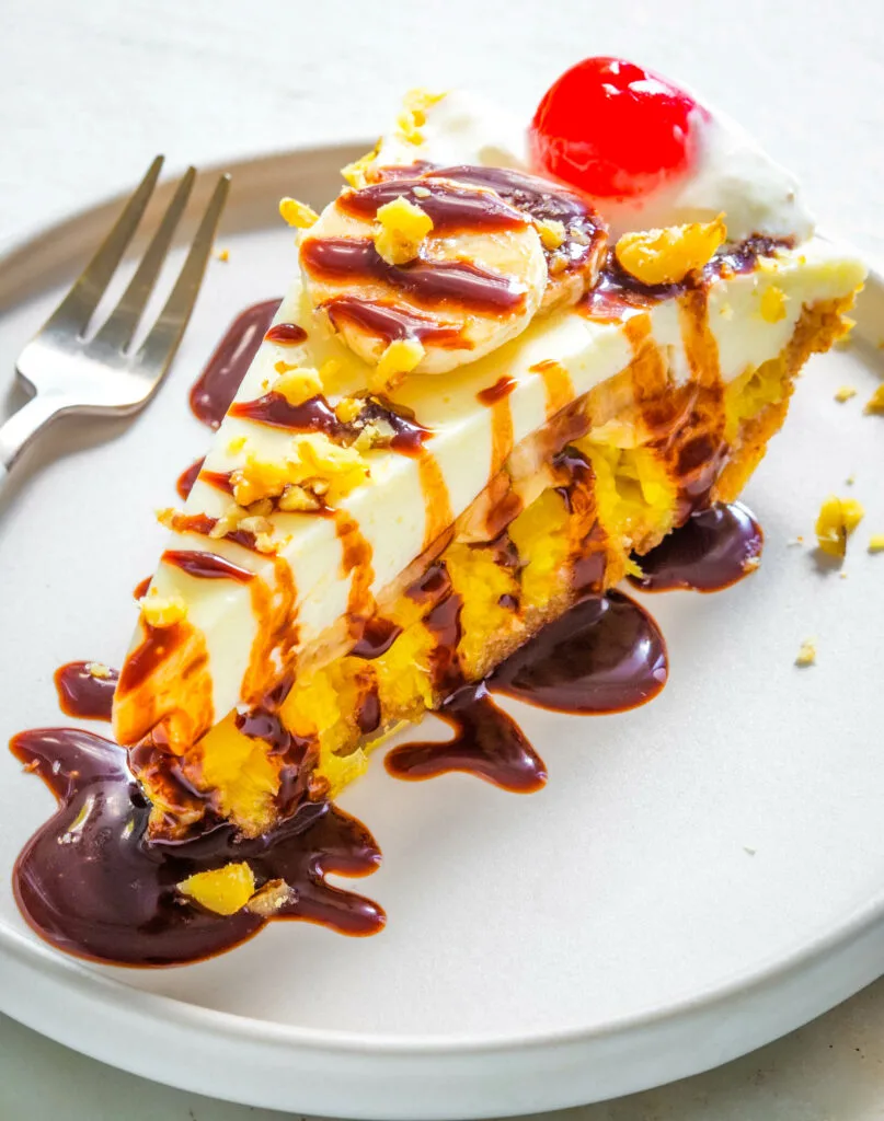 banana split pie on a plate with cherries and whipped cream and chocolate syrup