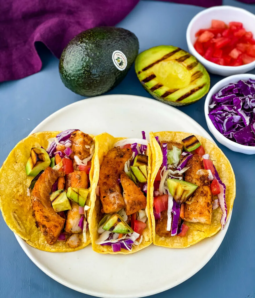 Blackened Fish Tacos on a plate with fresh avocado and cabbage