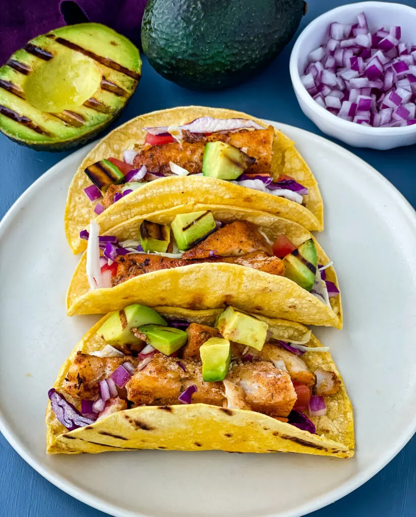 Blackened Fish Tacos on a plate with fresh avocado and cabbage