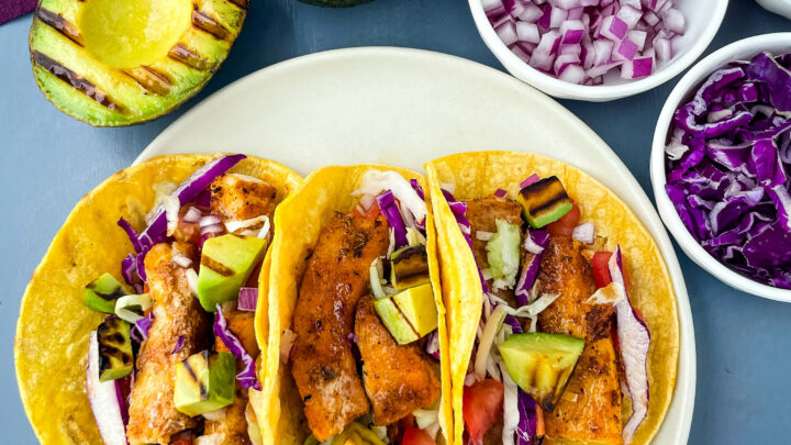 Blackened Fish Tacos on a plate with fresh avocado and cabbage