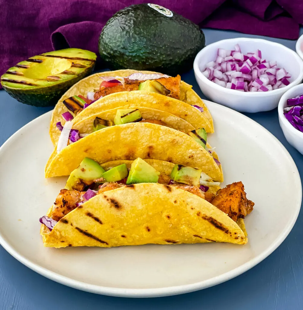 Blackened Fish Tacos on a plate with fresh avocado and cabbage
