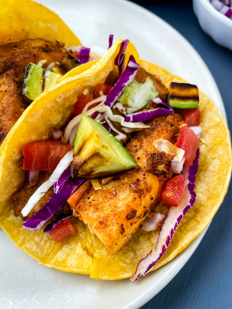 Blackened Fish Tacos on a plate with fresh avocado and cabbage