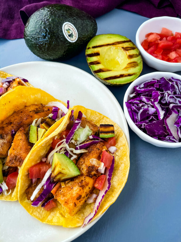 Blackened Fish Tacos on a plate with fresh avocado and cabbage