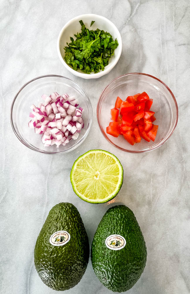 ripe avocados, chopped onions, chopped tomatoes, fresh lime, and cilantro in separate bowls