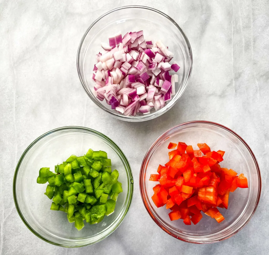 chopped onions, green peppers, and red onions in separate bowls