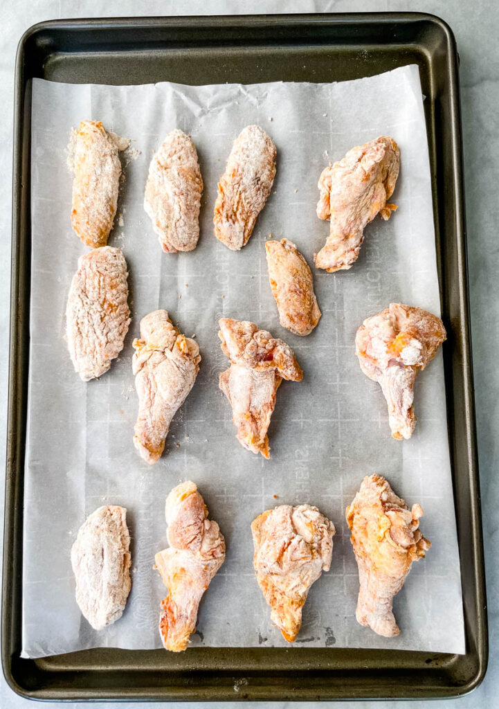 raw breaded chicken wings on a sheet pan