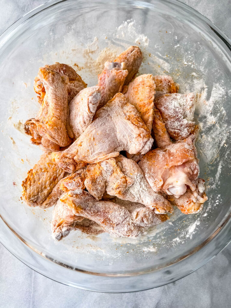 raw breaded chicken wings in a glass bowl