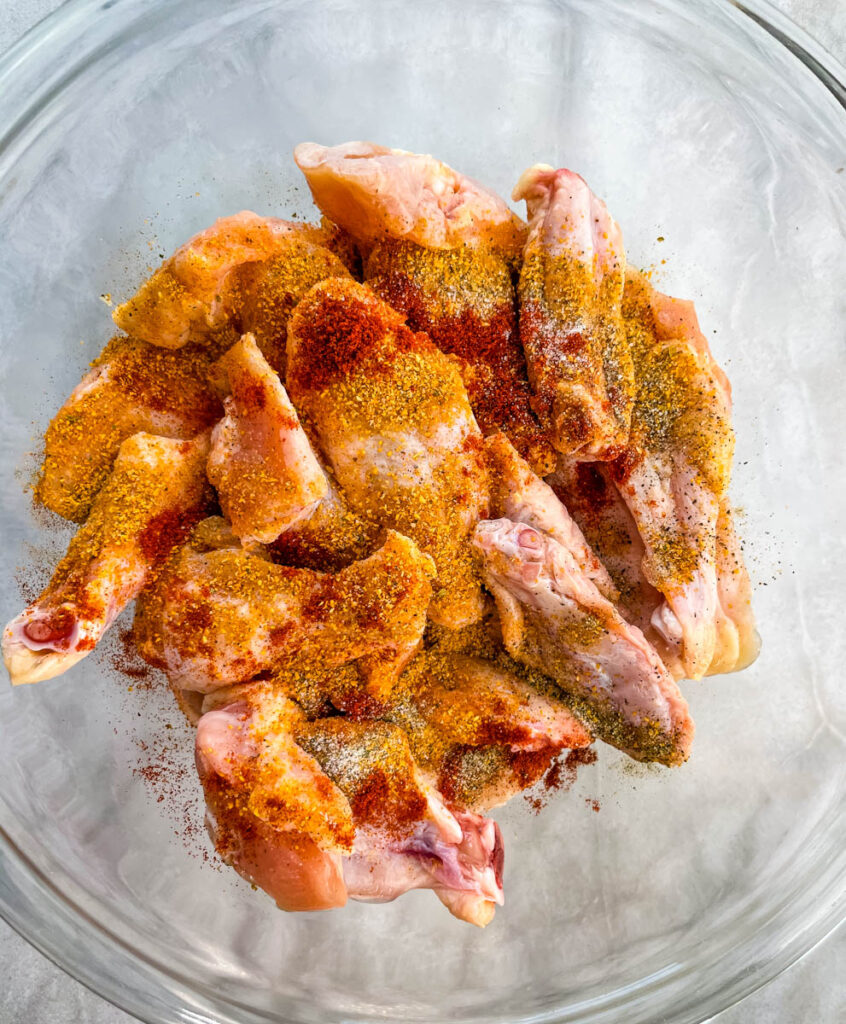 raw seasoned wings in a glass bowl