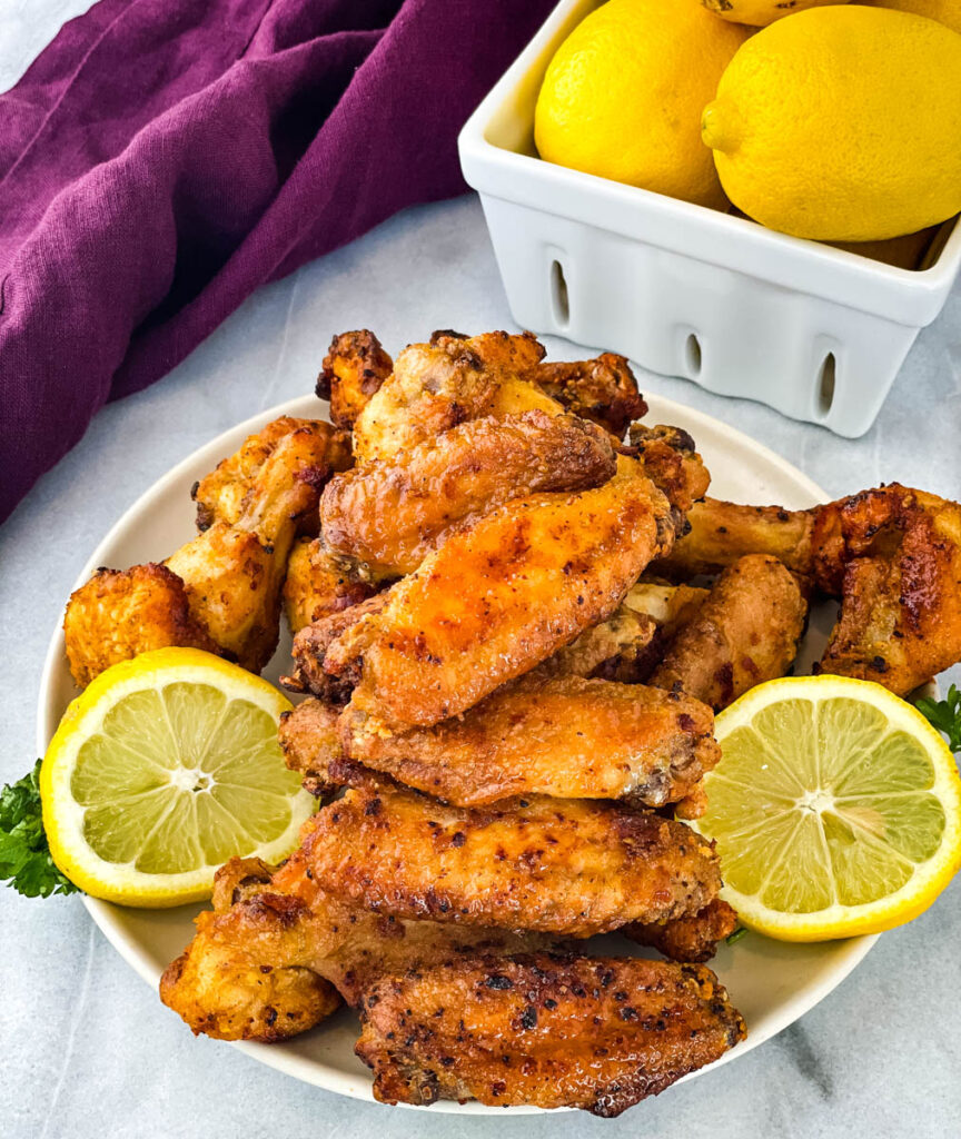 lemon pepper chicken wings on a plate with lemons