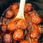 BBQ meatballs in a slow cooker with a wooden spoon
