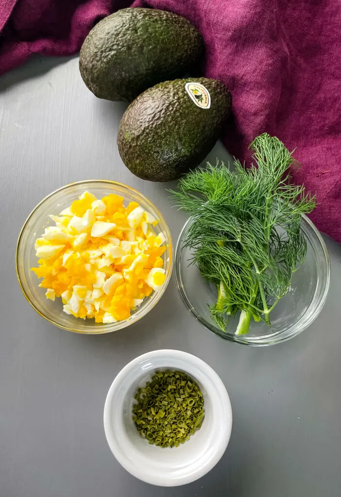 avocados, chopped eggs, and herbs in separate bowls