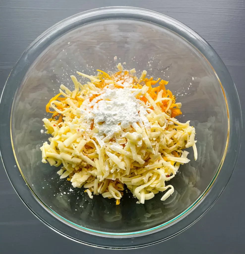 a glass bowl of cheddar cheese and pepper jack cheese