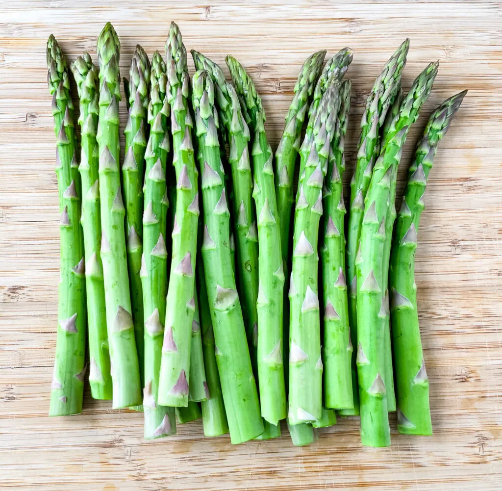 trimmed raw asparagus on a wooden cutting board