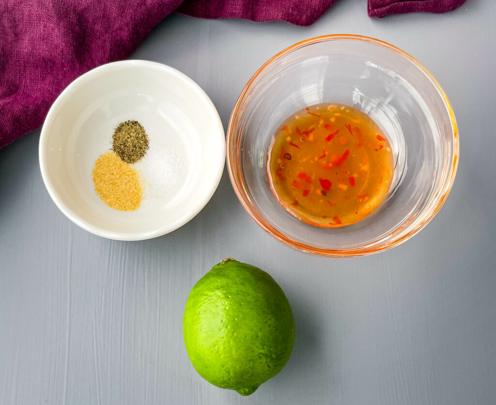 sweet chili sauce, a fresh lime, garlic powder and salt and pepper in bowls