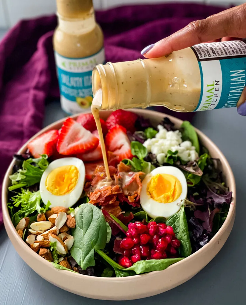 healthy breakfast salad in a bowl with bacon, eggs, and strawberries