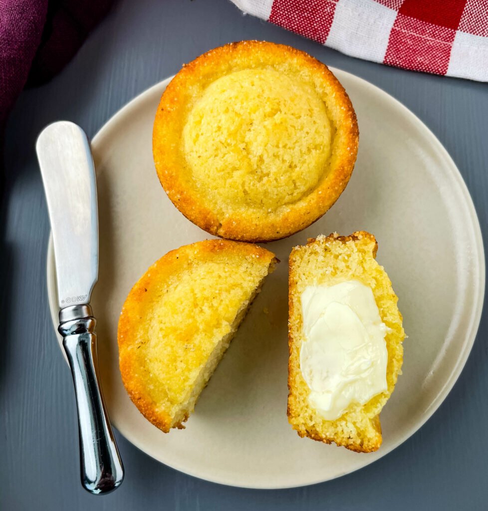 cornbread muffin sliced in half drizzled in butter