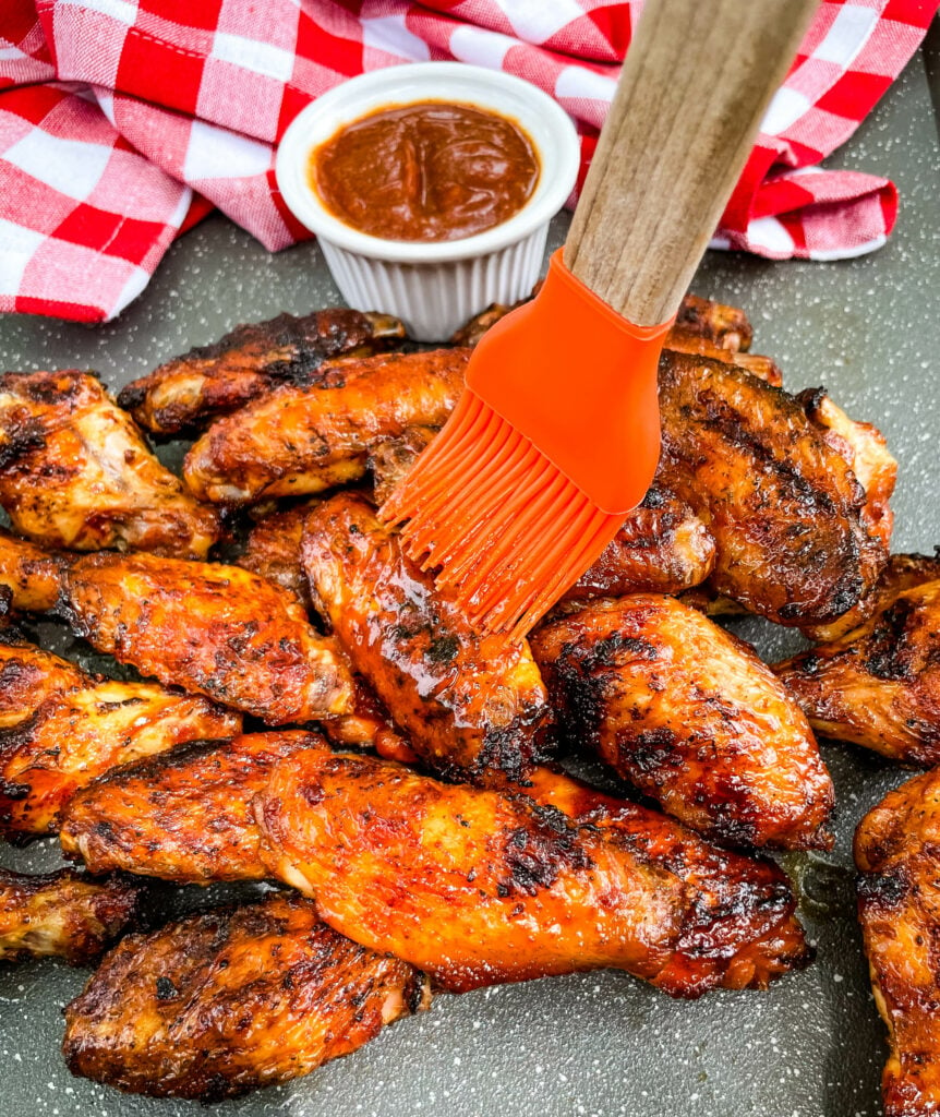 grill chicken wings glazed with BBQ sauce on a cooking brush