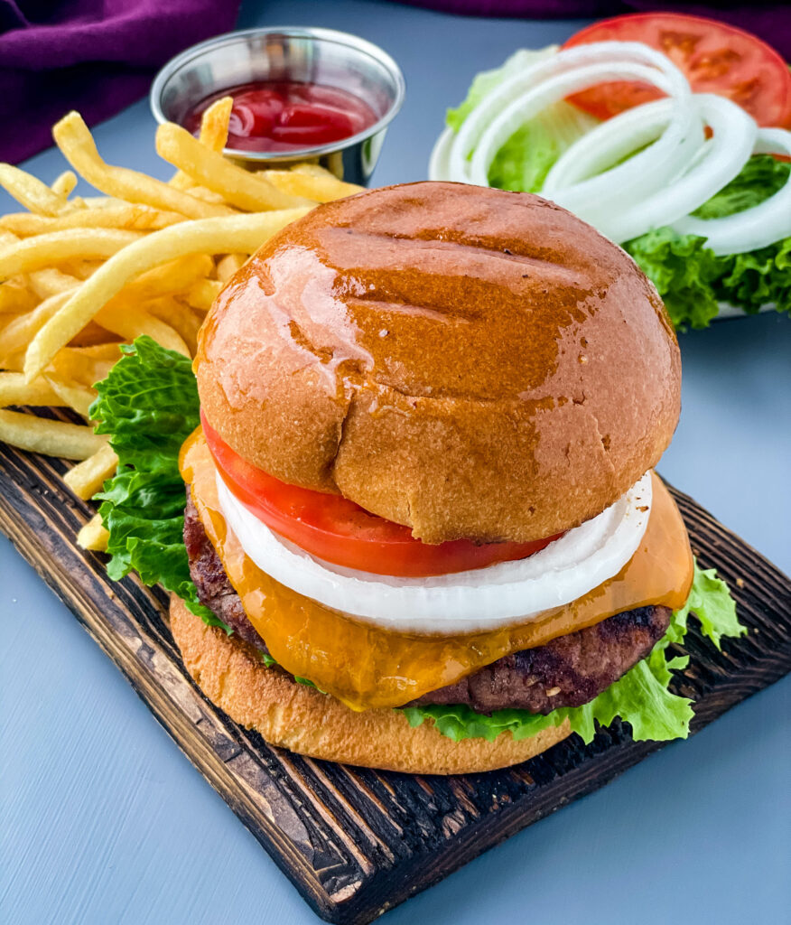 grilled cheeseburgers on a bun with a plate of fries