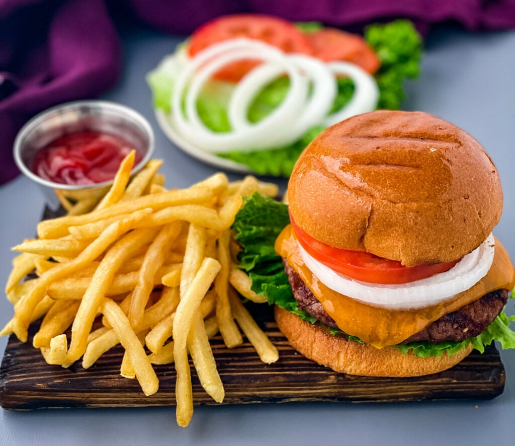 grilled cheeseburgers on a bun with a plate of fries