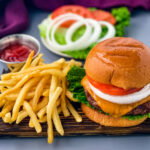 grilled cheeseburgers on a bun with a plate of fries