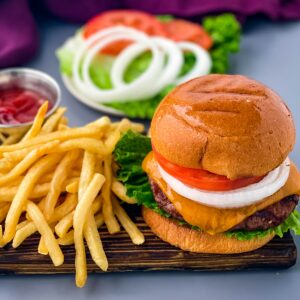 grilled cheeseburgers on a bun with a plate of fries