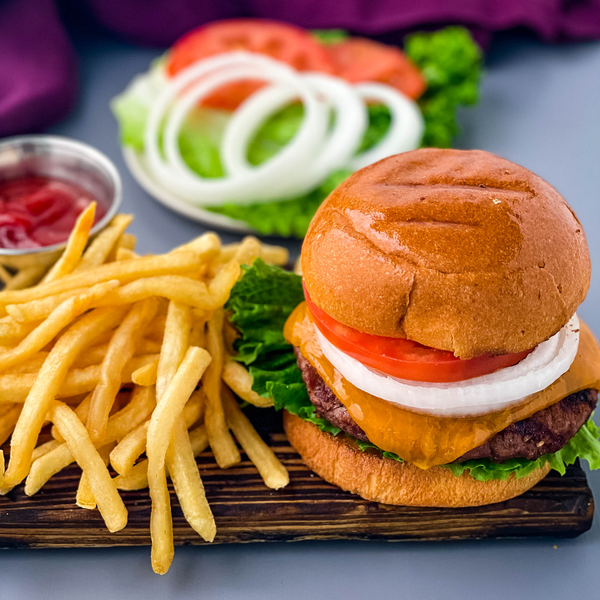 grilled cheeseburgers on a bun with a plate of fries
