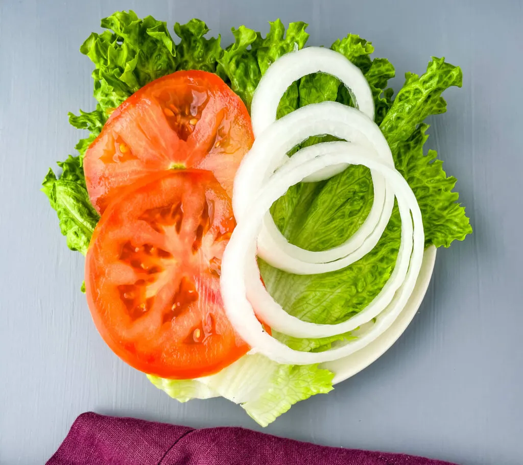 lettuce, sliced tomatoes, and sliced onions on a plate