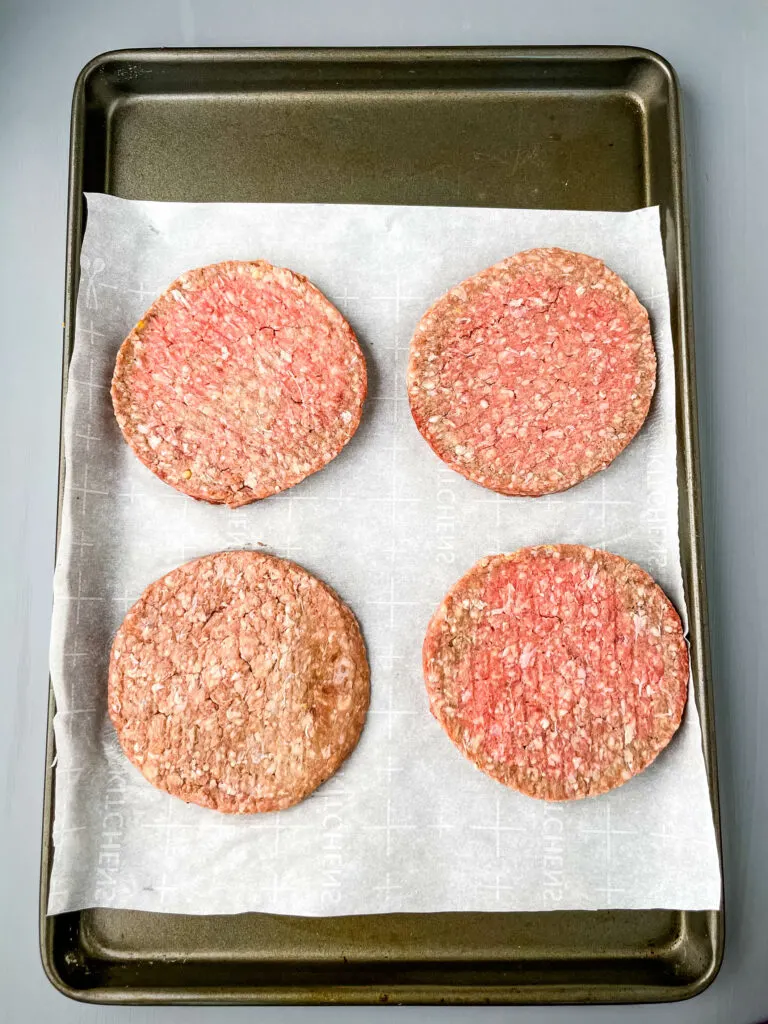 raw hamburger patties on a sheet pan