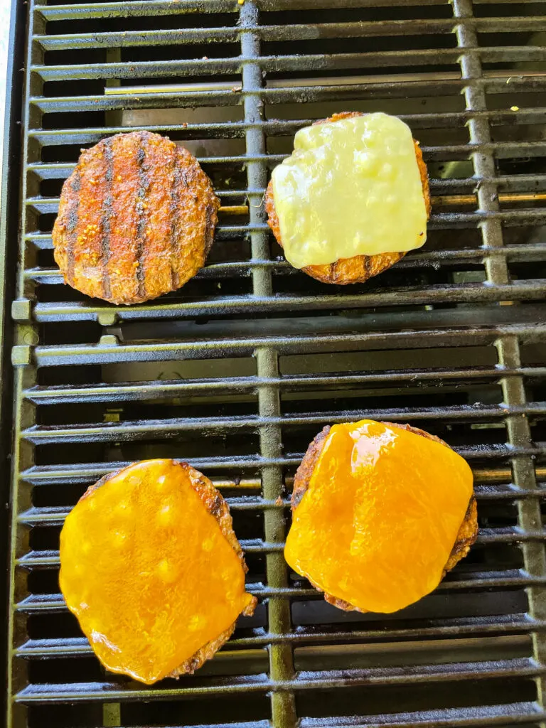 cooked hamburgers on a grill with cheese