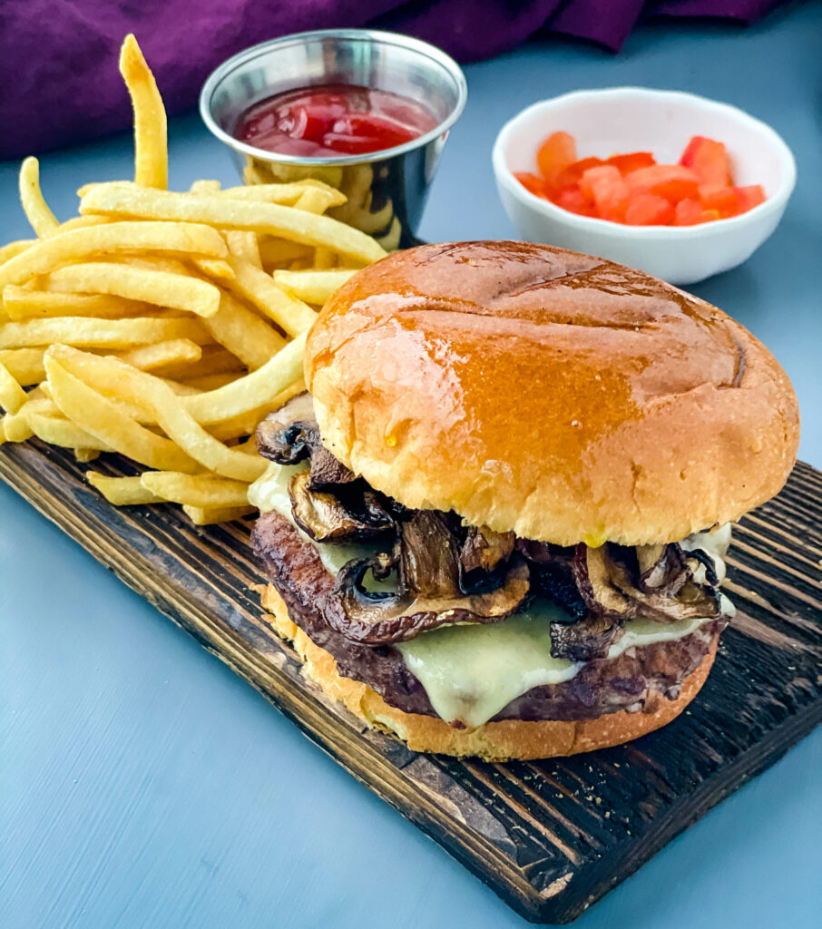 mushroom swiss burger on a plate with French fries