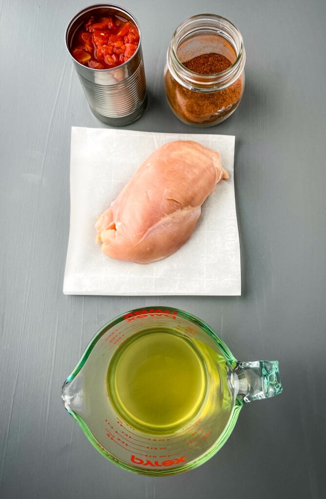 raw chicken breast, diced tomatoes, taco seasoning, and chicken broth in separate bowls