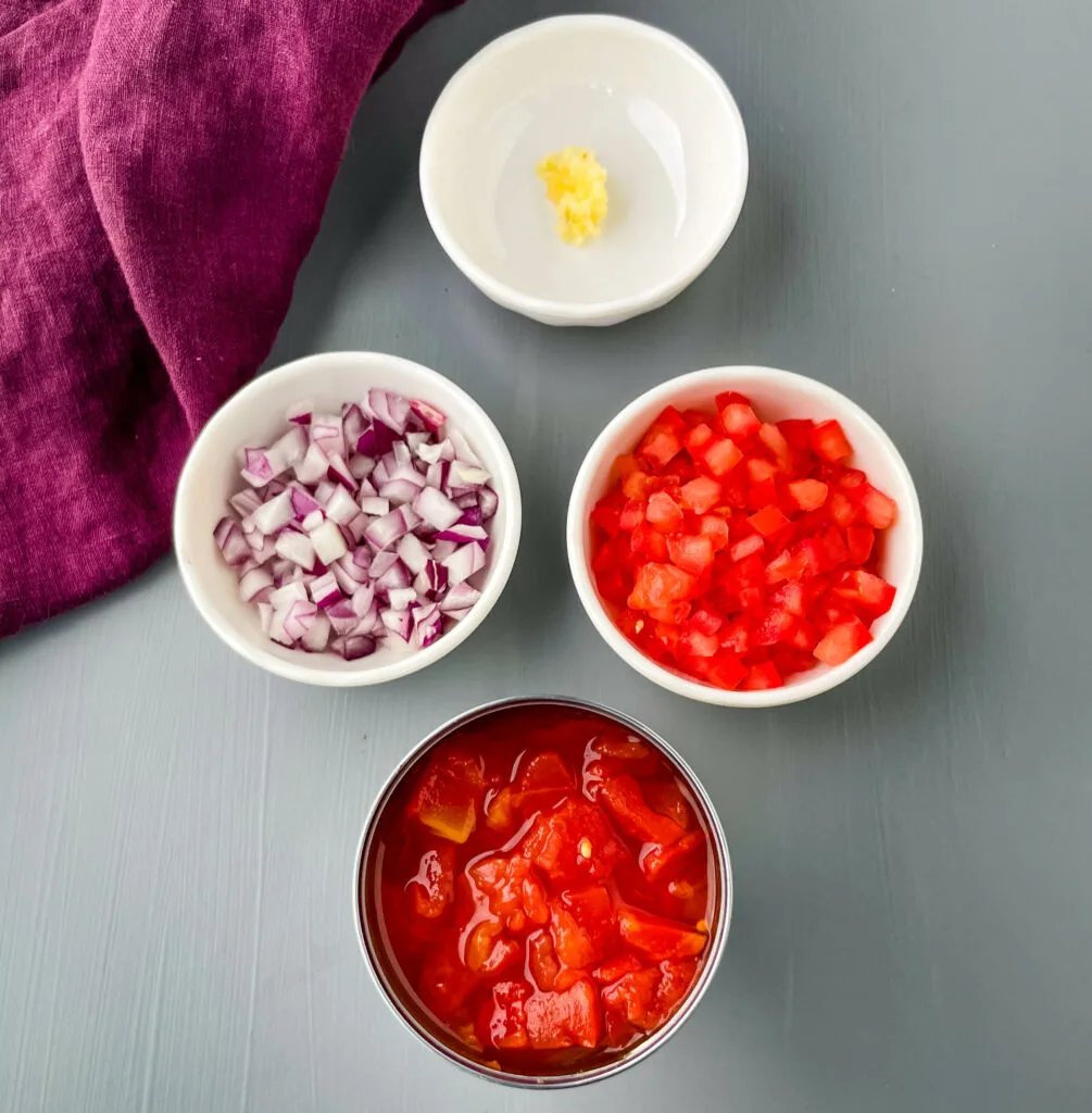 chopped onions, garlic, chopped tomatoes, and diced tomatoes in separate bowls